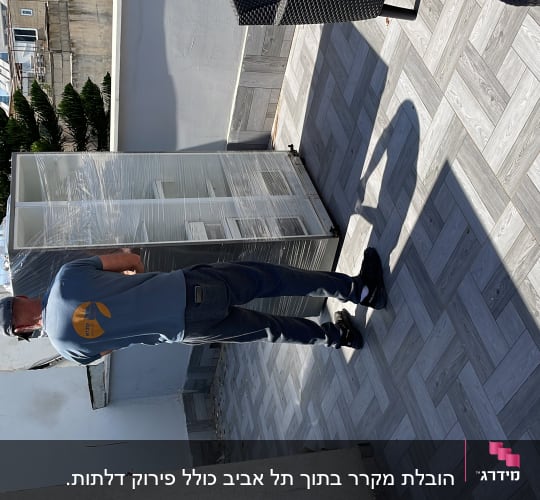 אדם מזיז ארון עטוף בניילון על מרפסת